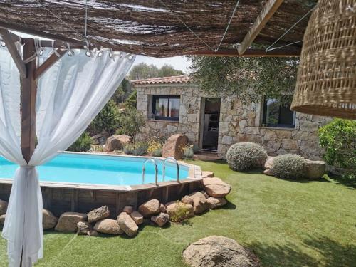 une cour arrière avec une piscine et un rideau blanc dans l'établissement Loue petite maison individuelle à Bocca Del oro, à Porto-Vecchio