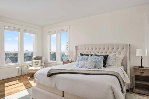 ein weißes Schlafzimmer mit großem Bett und Fenstern in der Unterkunft Casa de la Madre in Lincoln City