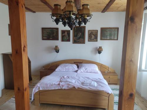 a bedroom with a wooden bed with a chandelier at Bambusz ház in Rábapaty