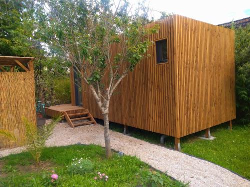 a small wooden house with a tree in a yard at La Cabane du figuier à Rambouillet in Rambouillet