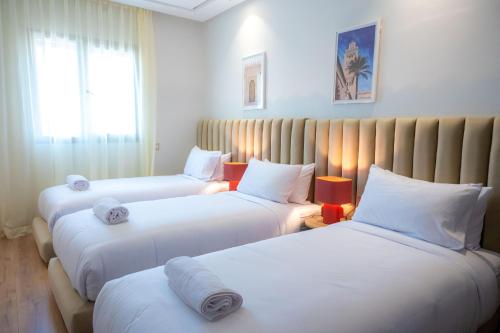 a hotel room with three beds with white sheets at TheCasaEdition - Gueliz Residency in Marrakech