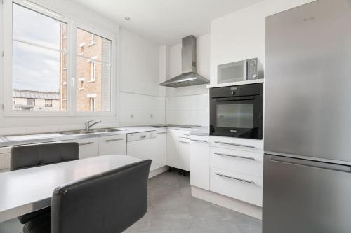 une cuisine blanche avec un évier et un micro-ondes dans l'établissement Splendide 2 pièce à Boulogne, à Boulogne-Billancourt