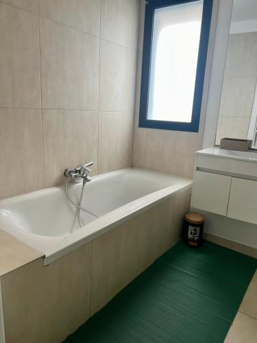La salle de bains est pourvue d'une baignoire blanche et d'une fenêtre. dans l'établissement Le cosy à Gagny - Proche Paris, à Gagny