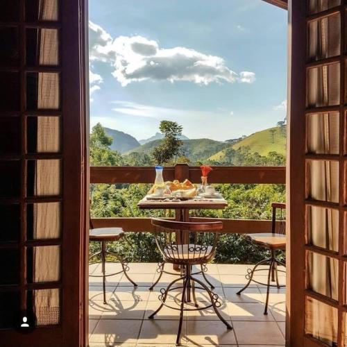 a table on a balcony with a view of the mountains at Chalés Nó da Madeira in Visconde De Maua