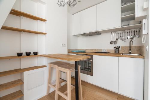 une cuisine avec des armoires blanches et une table en bois dans l'établissement A cosy Studio near Trocadero, à Paris