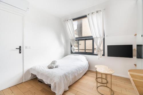 une chambre blanche avec un lit et une fenêtre dans l'établissement A cosy Studio near Trocadero, à Paris