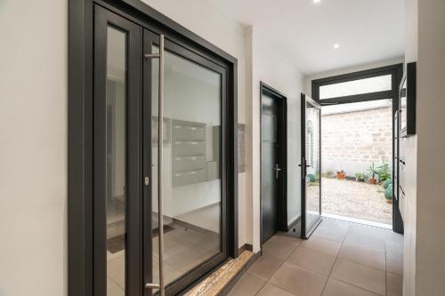 - un couloir avec des portes en verre noir et du carrelage dans l'établissement A cosy Studio near Trocadero, à Paris