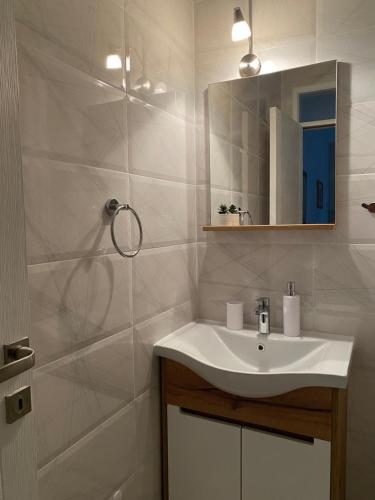 a white bathroom with a sink and a mirror at Apartments and Rooms Radivojević Niš in Niš