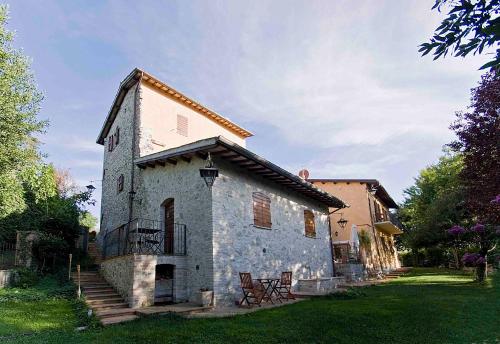 an old stone building with two chairs in a yard at Casale del Monsignore in Spoleto