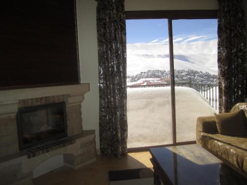 a living room with a fireplace and a large window at Cedars Palace in Al Arz