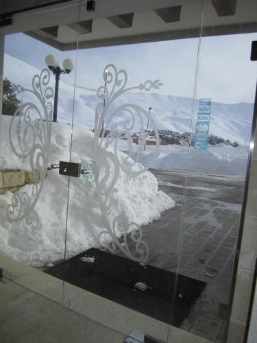 a glass window with snow on the side of a building at Cedars Palace in Al Arz