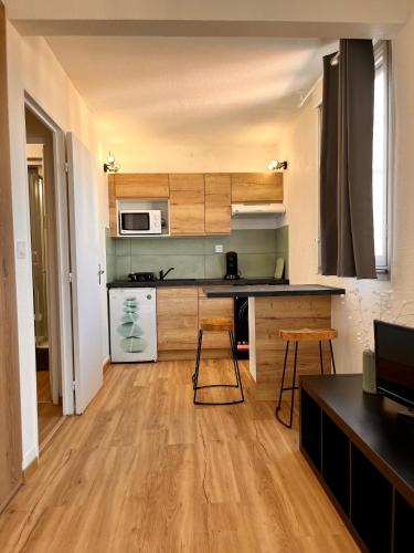 une cuisine avec des armoires en bois et un comptoir dans l'établissement Studio côté plage tout équipé vue sur le Canigou, à Canet