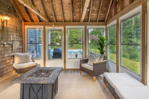 a screened in porch with a table and chairs and windows at Private Pool and Screened Deck Mashpee Home! in Mashpee