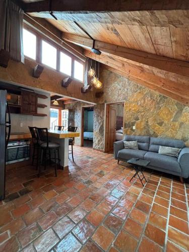 a living room with a couch and a stone wall at Casa 23 San Cristóbal in San Cristóbal de Las Casas