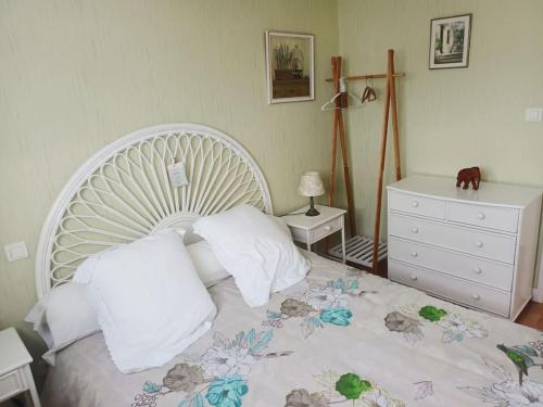 Cette chambre comprend un lit blanc avec des oreillers et une commode. dans l'établissement St-Marc T3 face mer à 20m de la plage, à Saint-Nazaire