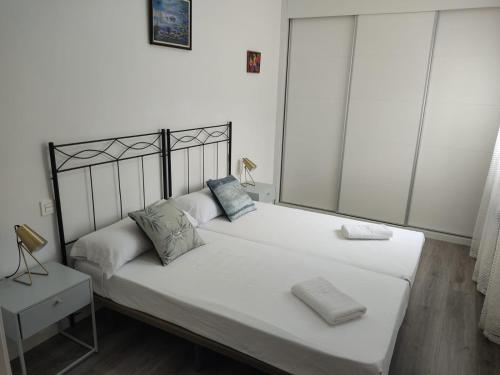 una camera da letto con un letto grande con lenzuola e cuscini bianchi di Céntrico Piso de 2 habitaciones a Saragozza