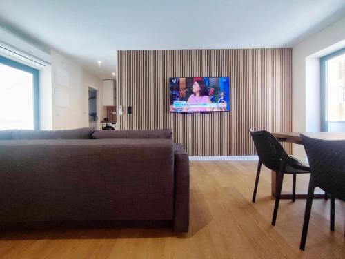 ein Wohnzimmer mit einem Sofa und einem TV an der Wand in der Unterkunft Casa Náutica T2 in Ovar