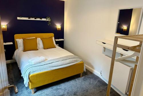 a small bedroom with a yellow bed with yellow pillows at Clock Tower Apartments 1 in Morecambe
