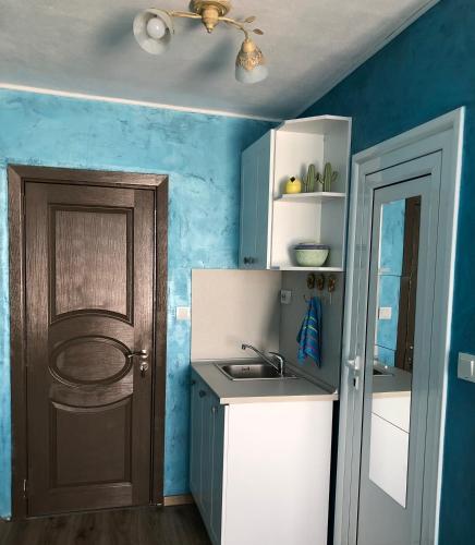 a small kitchen with blue walls and a door at Студио - Морско бягство in Primorsko