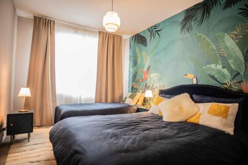 a bedroom with two beds and a tropical wallpaper at Appartement cosy vue mer face NAUSICA in Boulogne-sur-Mer