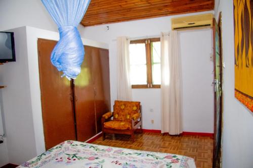 a bedroom with a bed and a chair and a window at Hostel Pensão Ya Mute in Chimoio