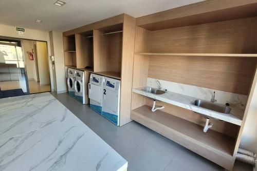 a bathroom with two sinks and a washer and dryer at Studio Novo Alto Padrão - Centro in Curitiba