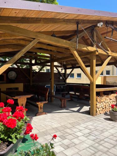 a wooden pavilion with benches and red flowers at Vila Liberta in Poprad