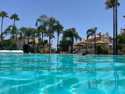 a large swimming pool with palm trees in the background at Modern Sea & Golf View 2-Bedroom Apartment with Pool and Terrace in Calanova in Mijas