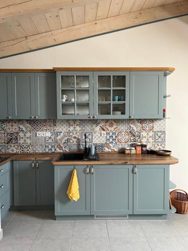 a kitchen with blue cabinets and a tile wall at Vila Liberta in Poprad