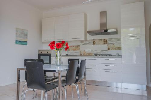 a kitchen with a table with chairs and a vase with red flowers at Halanus Agriexperience in Alanno
