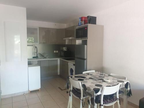 une cuisine avec une table avec des chaises et un réfrigérateur dans l'établissement T2 parking avec balcon, à Nîmes