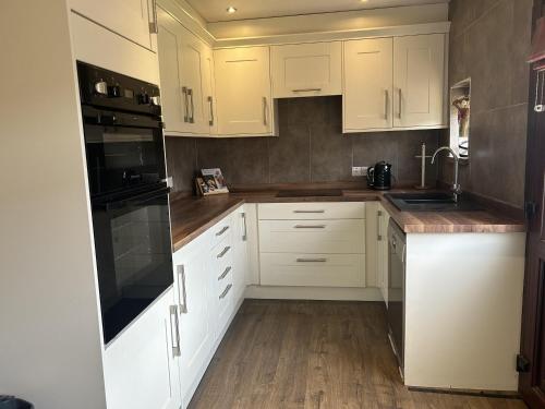 a white kitchen with white cabinets and wooden floors at wonderful 4 bedroom cottage sleeps 8 in Carlisle