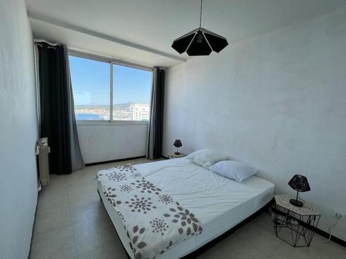 une chambre avec un lit et une grande fenêtre dans l'établissement Panorama exceptionnel pour ce T4 en bord de mer, à Toulon