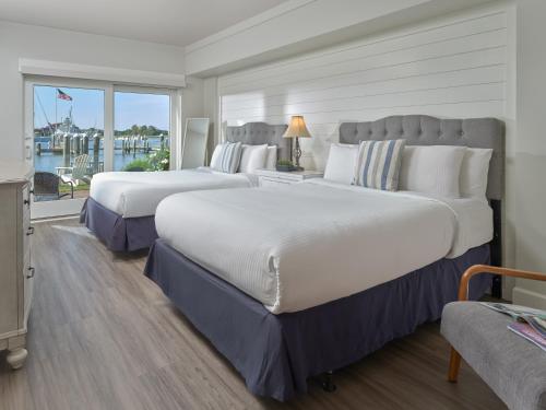 two beds in a hotel room with a large window at St Michaels Harbour Inn, Marina and Spa in Saint Michaels