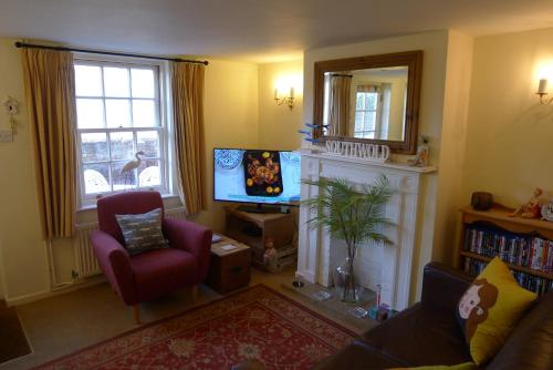 a living room with a tv and a fireplace at Weavers Cottage in Southwold