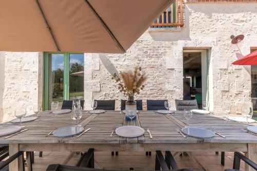 une longue table en bois avec des chaises et un parasol dans l'établissement 6 ch, 5 salle de bain, 25 minutes du Zoo de Beauval et Chambord, 12 pers, à Chémery