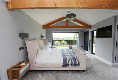 a bedroom with a white bed and a large window at Spectre Hot Tub Retreat - Harrogate in Pannal