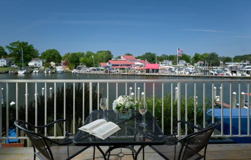 a table with wine glasses and flowers on a balcony at St Michaels Harbour Inn, Marina and Spa in Saint Michaels