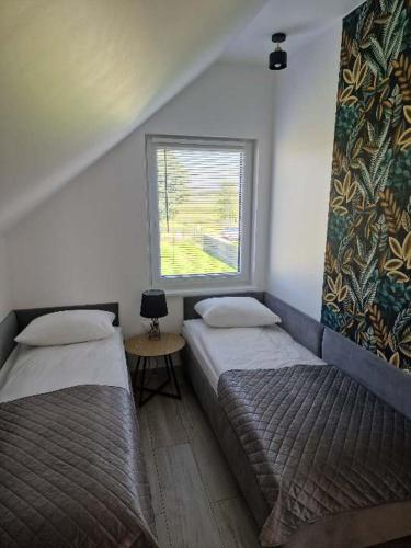 two beds in a small room with a window at Dom Choczewo Zielony Zakątek in Choczewo