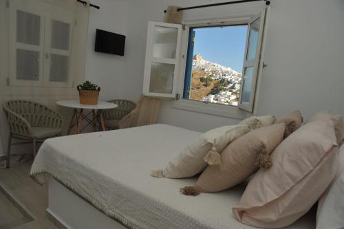 a bedroom with a bed with pillows and a window at Belvedere Studios in Astypalaia Town