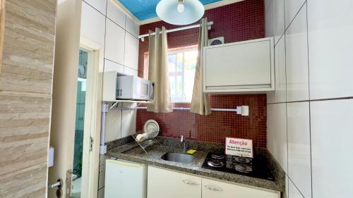 a small kitchen with white cabinets and a sink at Hotel das Palmas in Florianópolis