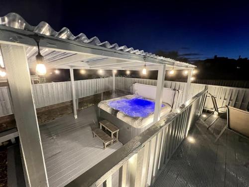 a deck with a hot tub under a pergola at night at Numero Venti Aparthouse wifi parking Hot Tub in Newcastle upon Tyne