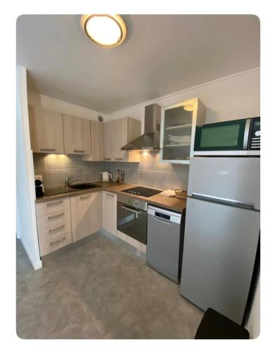 une cuisine avec des armoires blanches et un réfrigérateur blanc dans l'établissement Appartement 6 couchages rez-de-jardin à 5 mn de la plage, au Cap d'Agde