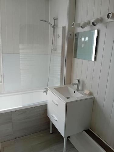 une salle de bain blanche avec un lavabo et un miroir dans l'établissement Maison à Eu proche centre ville et baie de Somme, à Eu