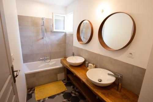 une salle de bain avec un lavabo et deux miroirs au mur dans l'établissement Maison avec jardin, à Saumane-de-Vaucluse