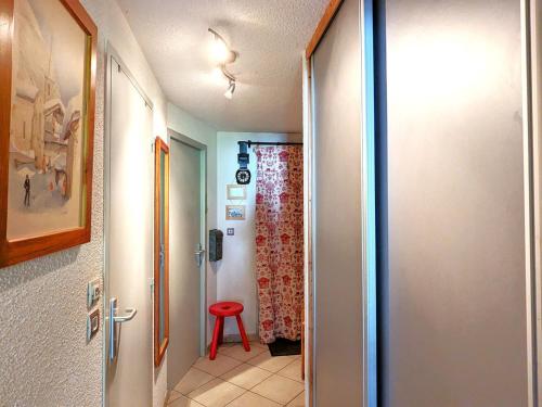 un couloir avec une porte menant à une pièce avec un tabouret rouge dans l'établissement Appartement cosy au cœur de La Clusaz, ski au pied, avec terrasse et WiFi - FR-1-459-229, à La Clusaz
