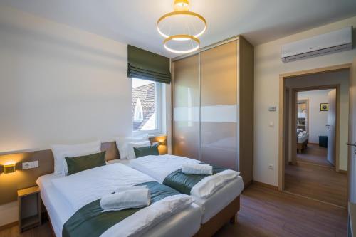 a bedroom with a large bed with white sheets and green pillows at Aurea Apartman in Siófok