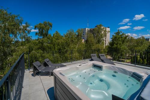a hot tub on a balcony with two chairs at Aurea Apartman in Siófok