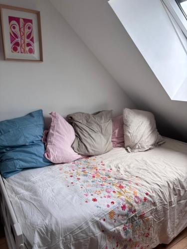 - un lit avec des oreillers colorés dans l'établissement Charmante chambre cosi, à Bretteville-sur-Odon