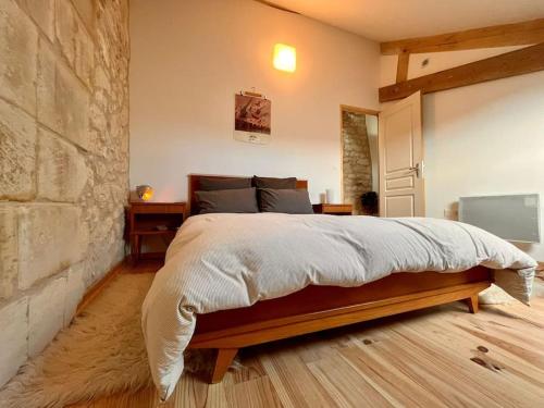 une chambre avec un lit et un mur en pierre dans l'établissement Near châteaux and charming villages, à Cravant-les-Coteaux